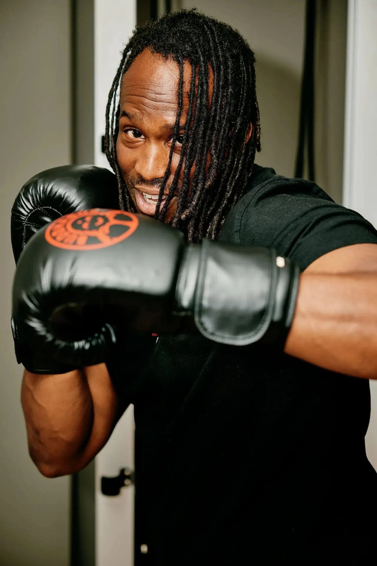 Man in black boxing gloves demonstrating a punch stance during a boxing training session.