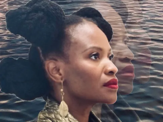 Woman in profile wearing dark clothing and gold earrings, positioned against rippling water backdrop.