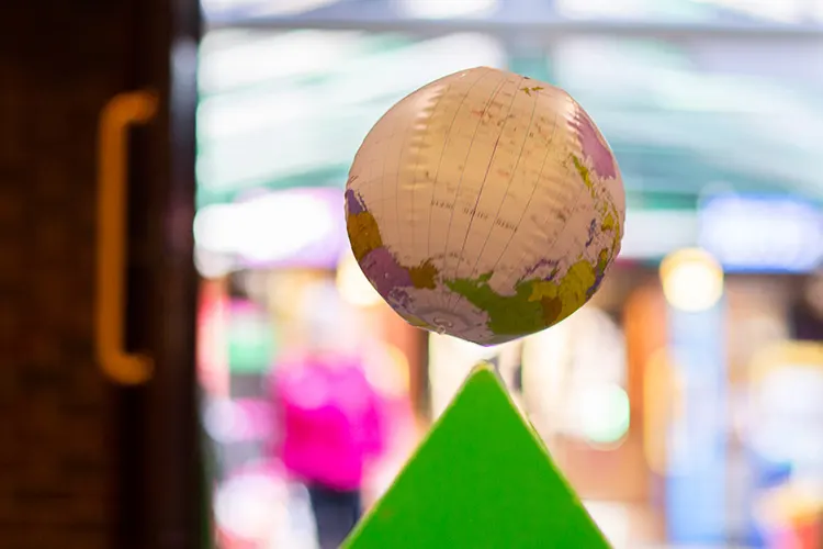 A illuminated paper globe resting on a bright green cone-shaped structure indoors.