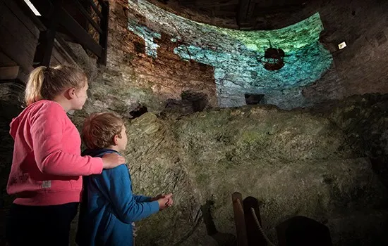 Two children viewing illuminated stone walls inside a castle ruin.
