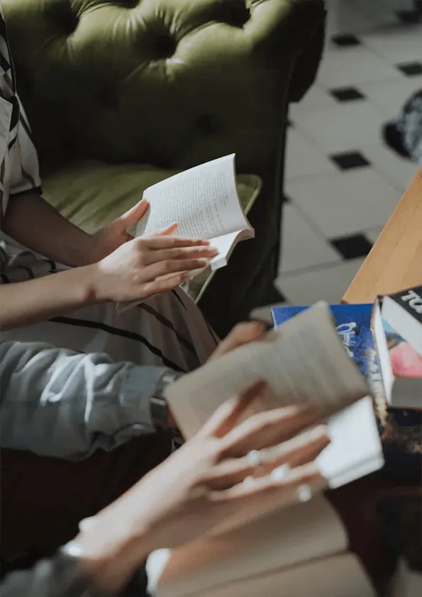 Children's hands holding open books during a reading activity in an indoor venue.