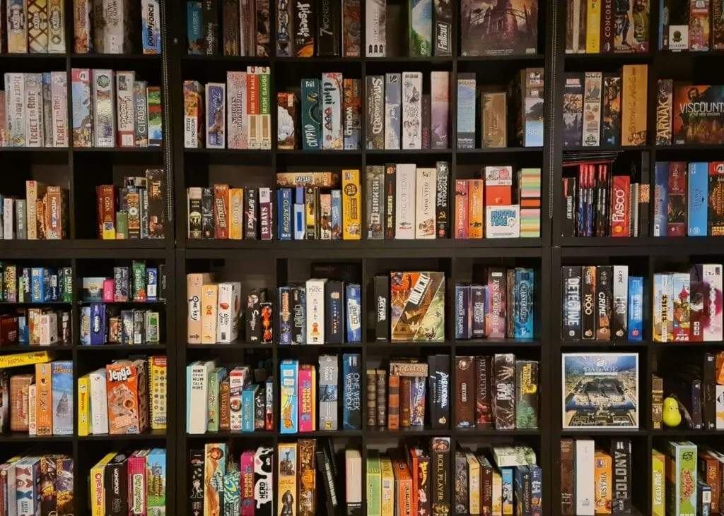 Shelves displaying a large collection of boxed board games and tabletop games organised by rows.