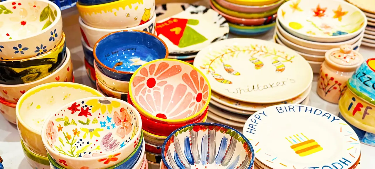 Colourful hand-painted ceramic bowls and plates with floral and geometric designs displayed on a table.