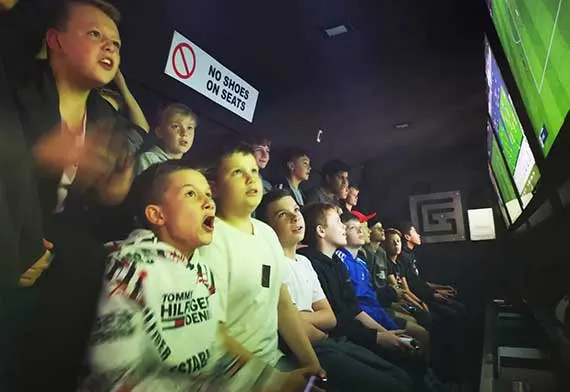 Children and young people sitting in a gaming van playing video games on screens.