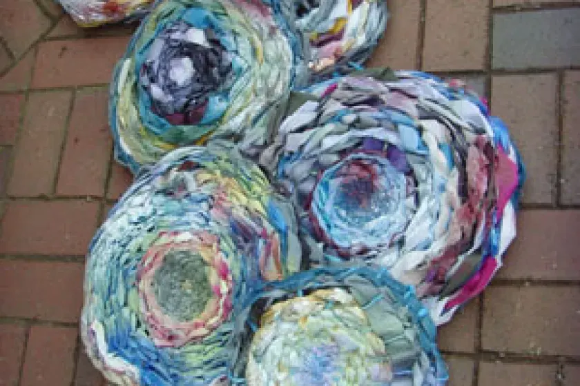 Colourful spiral-patterned fabric artworks arranged on a brick pavement.