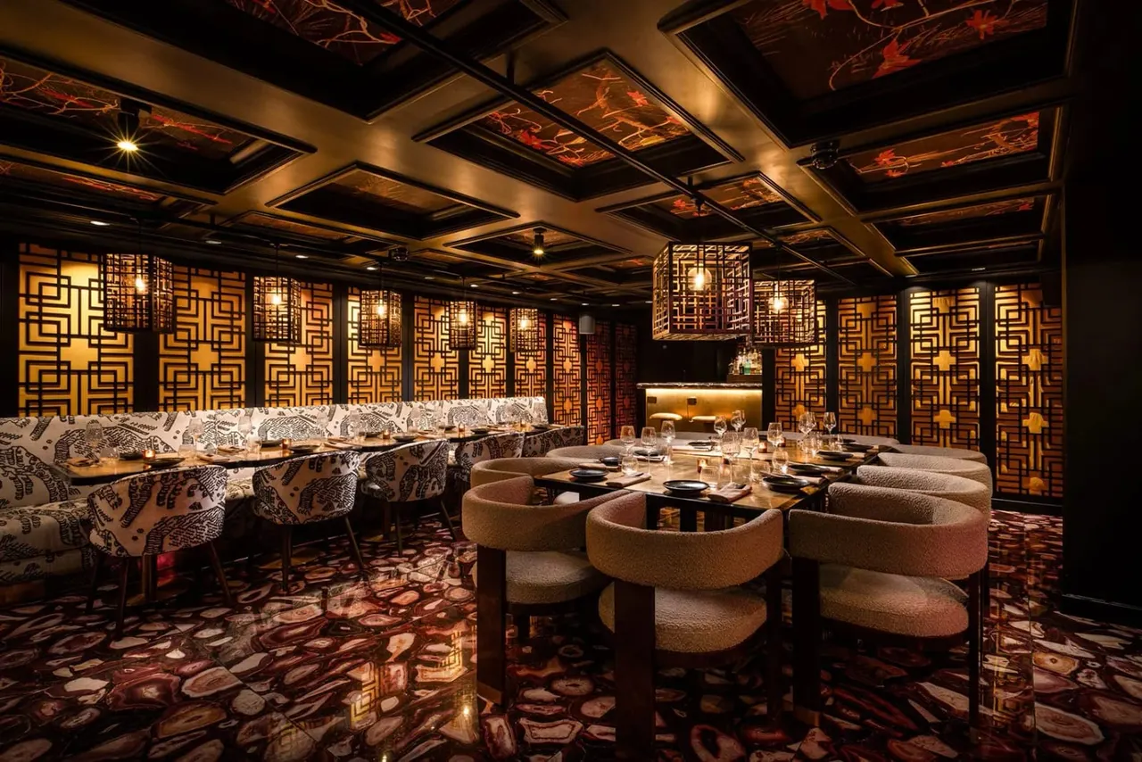 Upscale restaurant dining room with geometric wooden screens, warm lighting, and tables set for fine dining.