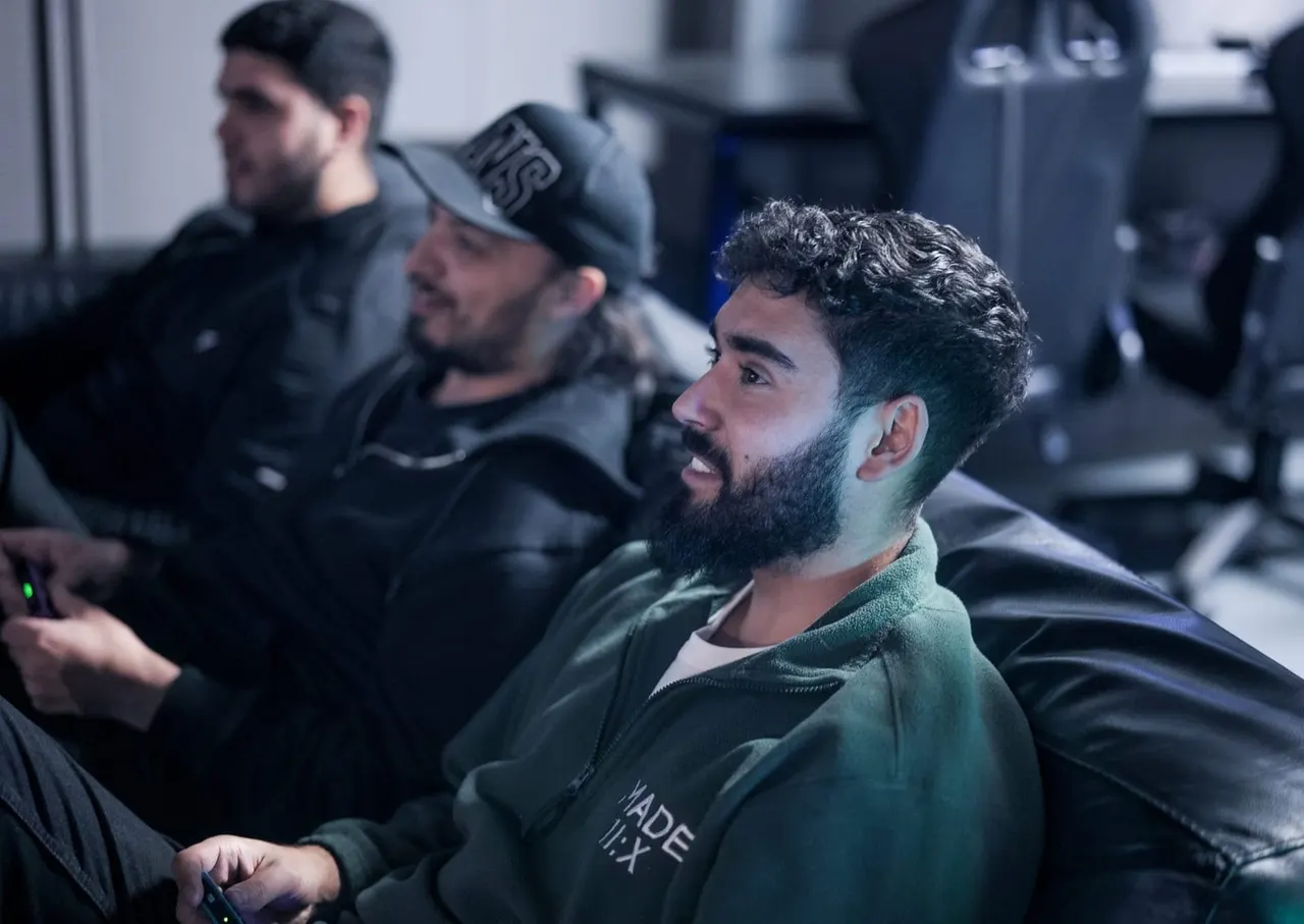 Men seated in gaming chairs holding controllers during a virtual reality or gaming session.