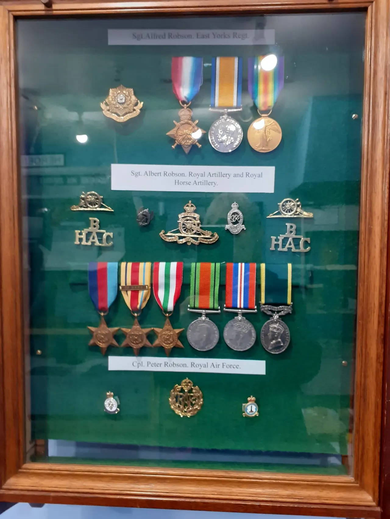 Display case with military medals, badges and insignia honouring three servicemen from the Last Yorks Regiment, Royal Artillery and Royal Air Force.