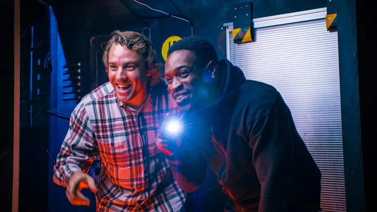 Two people smiling at a laser tag or indoor gaming arena with neon lighting and geometric wall decorations.