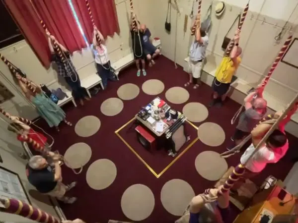 Aerial view of people arranged in a circle around a central display in a hall with burgundy floor and draped fabric.