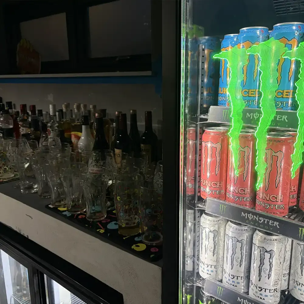 Bar counter displaying bottles of spirits and glasses on the left, with a refrigerated display of energy drinks on the right.