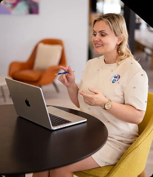 Woman working at laptop whilst seated in yellow chair at modern leisure venue.