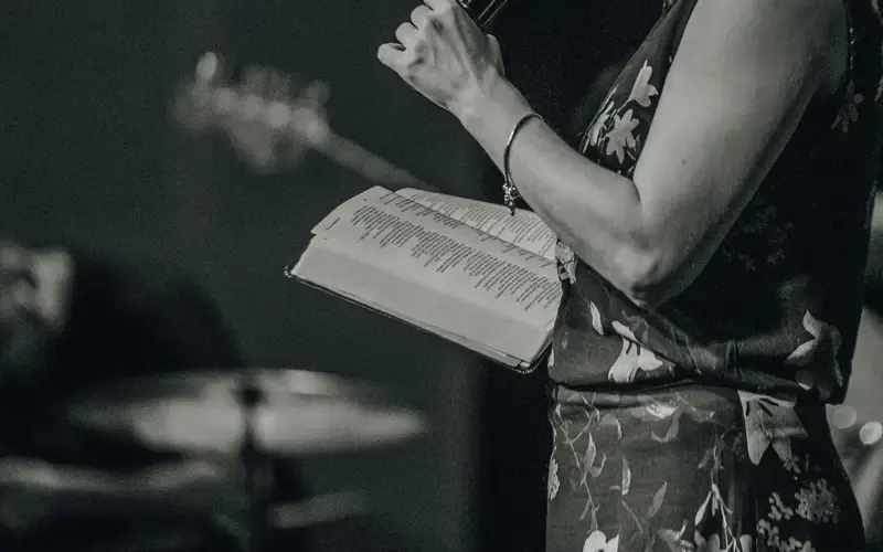 Person holding an open book during a live performance or event indoors.