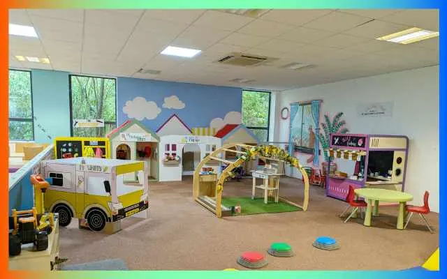 Bright, colourful indoor play area with toy vehicles, play houses, and activity stations for young children.