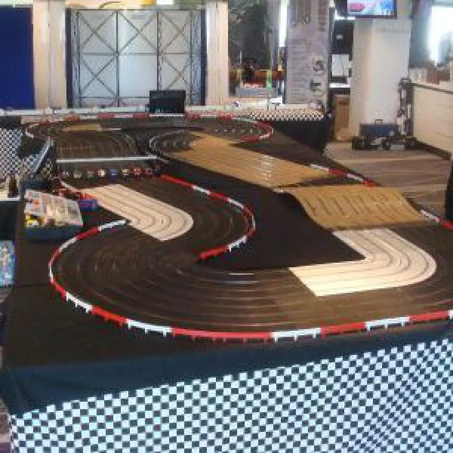 Indoor slot car racing track with multiple lanes and red and white barriers in an entertainment venue.