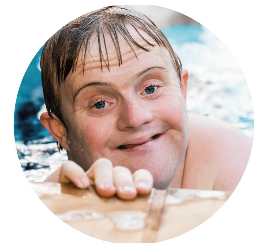 Young person enjoying the sea, standing in shallow water at the beach with a cheerful expression.