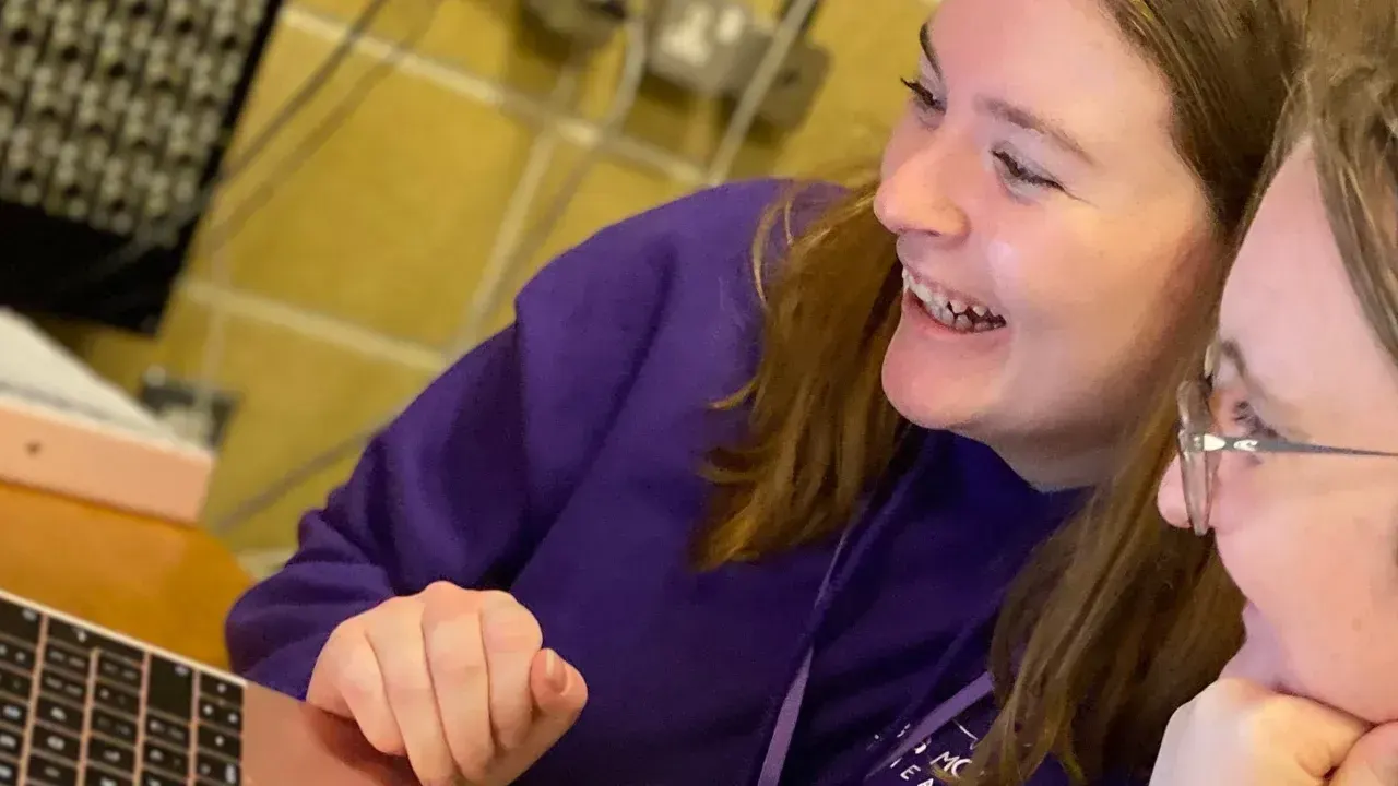 Child in purple top laughing whilst playing an arcade game at an indoor leisure venue.