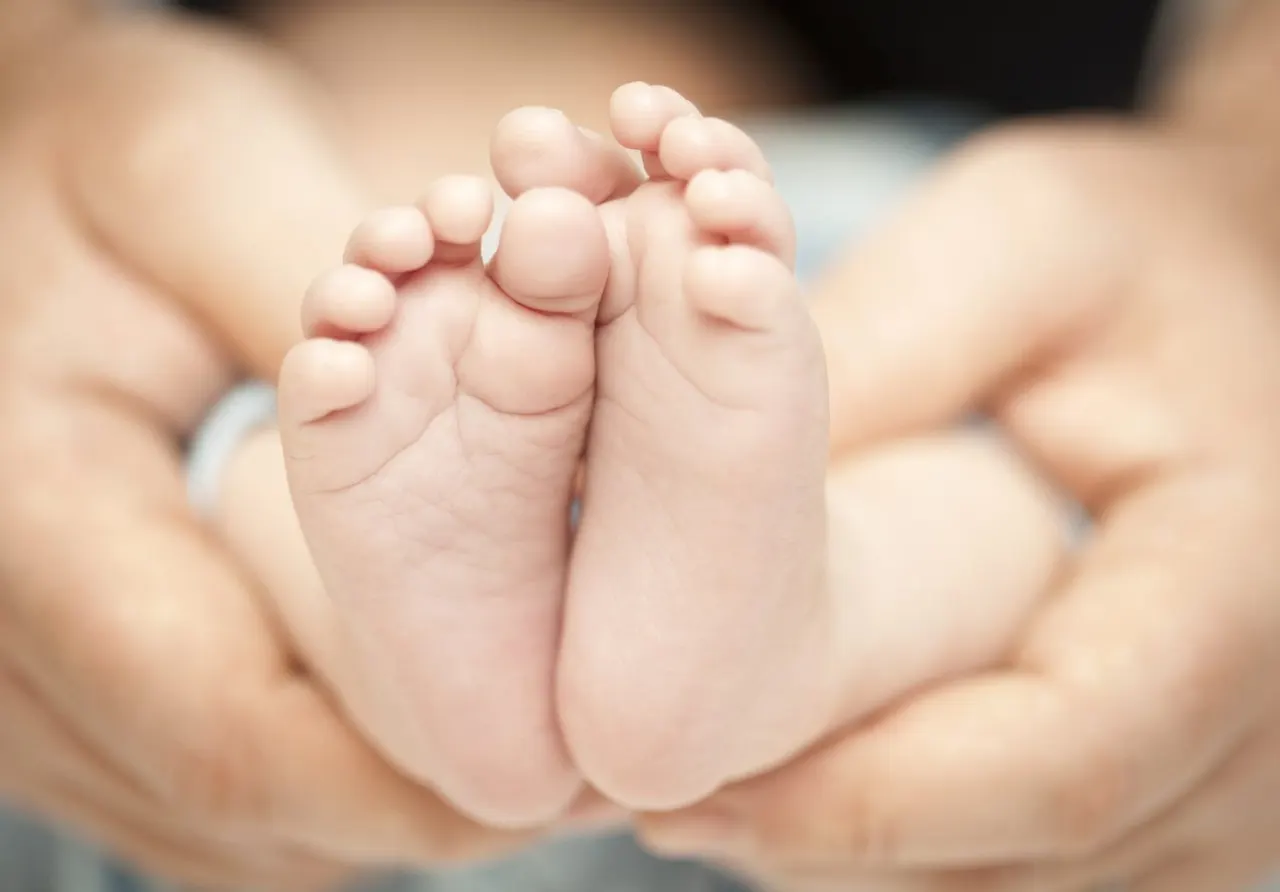 Close-up of a baby's feet held in an adult's hands.