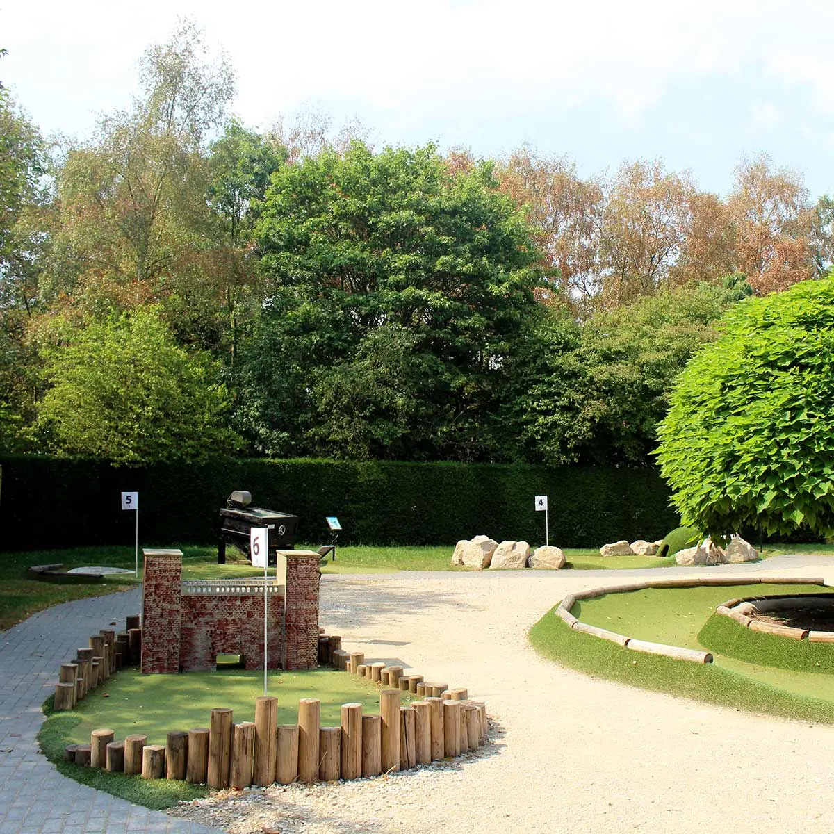 Outdoor adventure golf green with wooden log borders and brick castle obstacle at Rufford Abbey