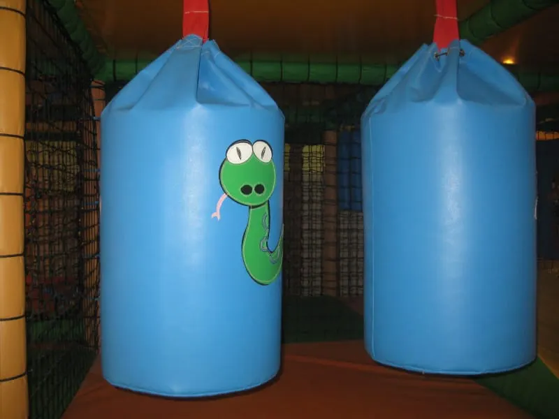 Two blue cylindrical play structures with cartoon character designs inside an indoor soft play area.
