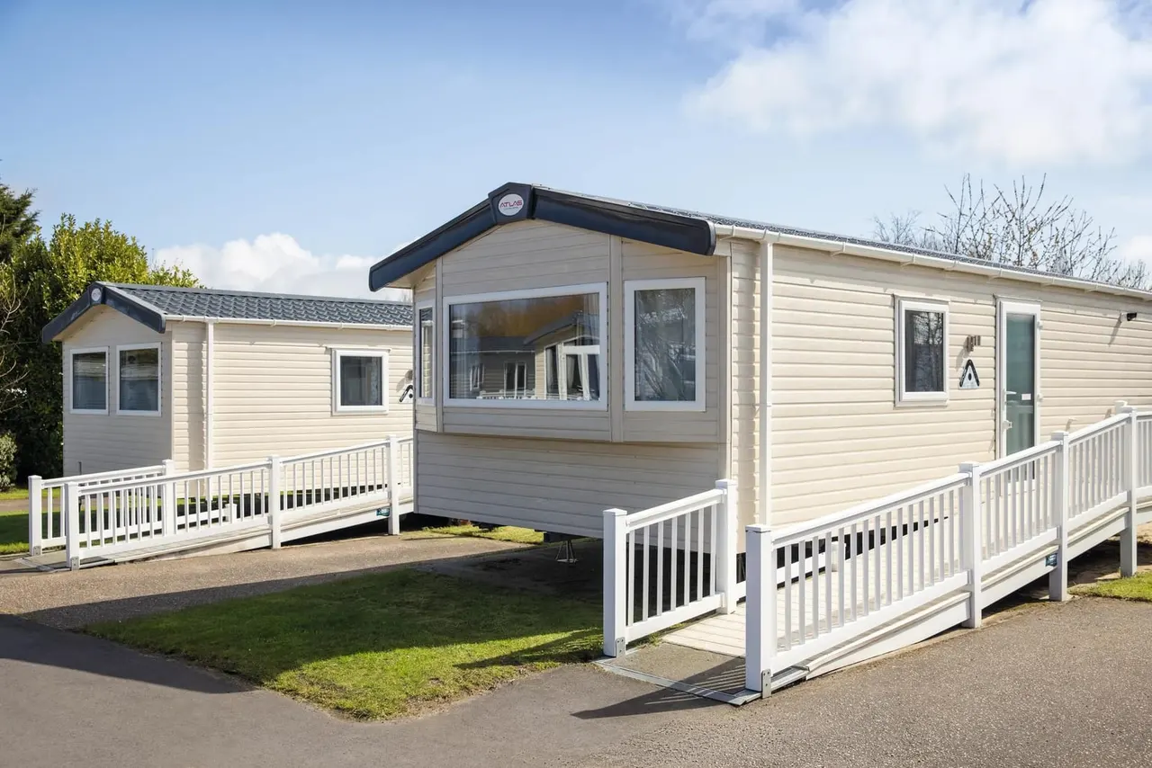 Modern static caravans with cream cladding and white railings arranged on a holiday park site.