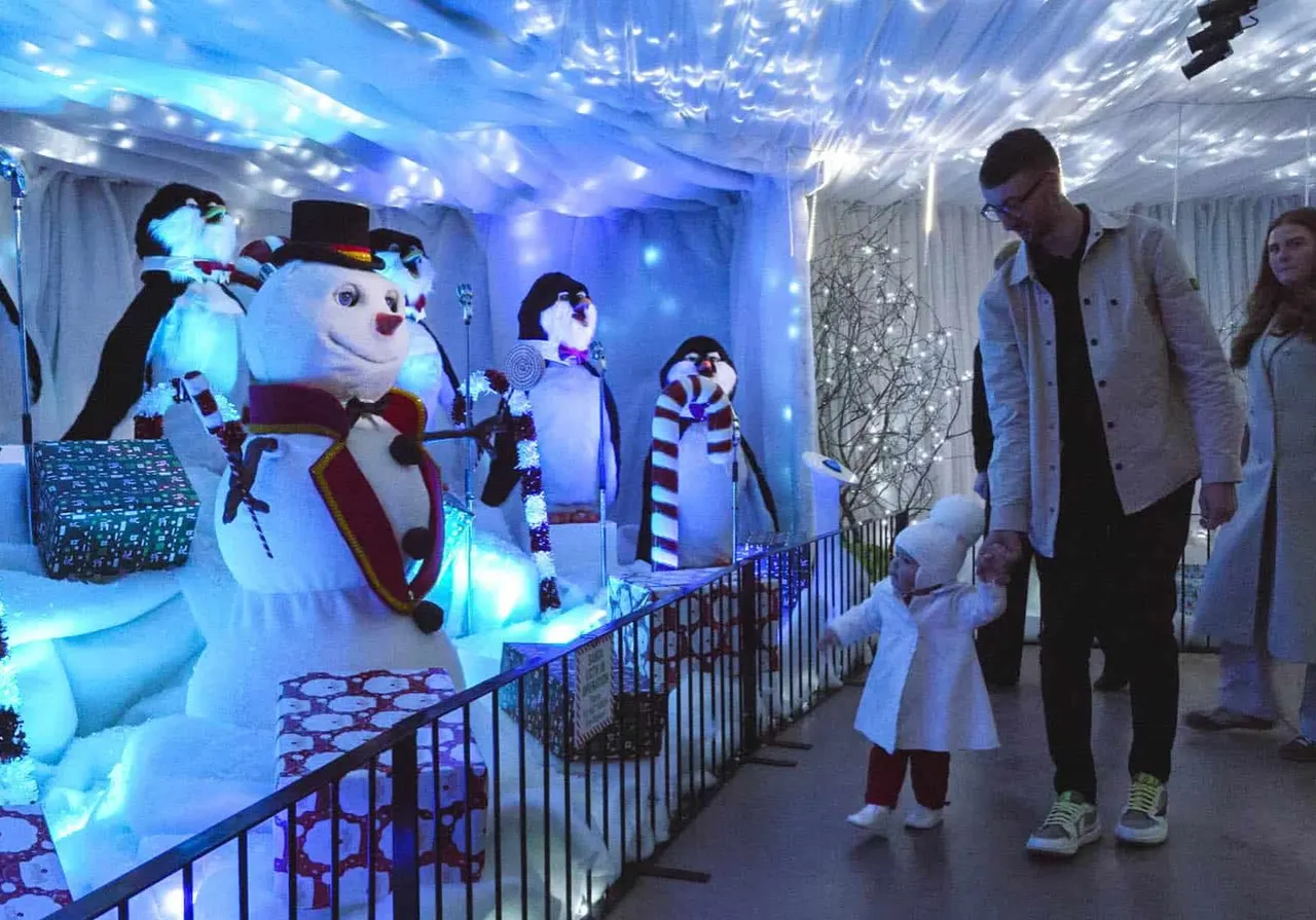 Families viewing illuminated snowman figures and festive displays in an indoor winter-themed attraction with blue lighting.