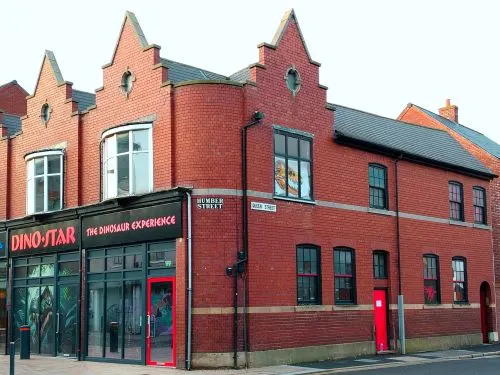 Red brick building with distinctive stepped gable roofs and Dino-Star storefront at ground level.