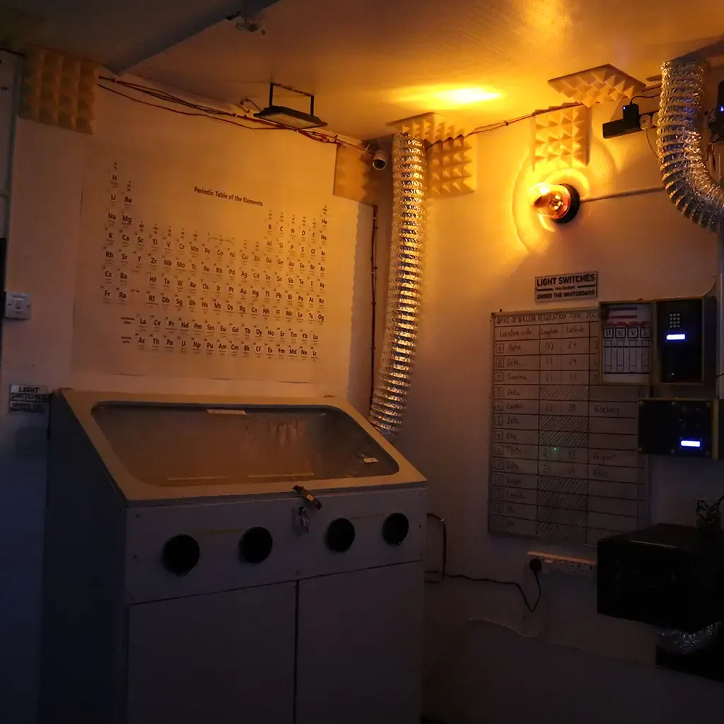 Interactive science-themed escape room with periodic table, glowing heat lamps, control panels and experimental equipment displays.
