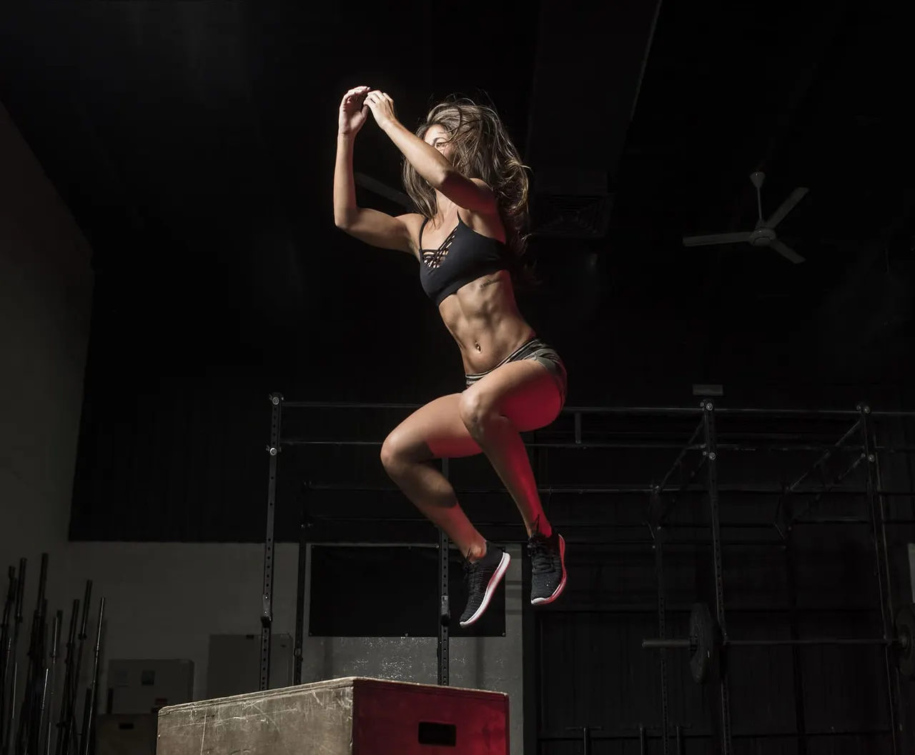 Woman in mid-air performing a box jump during a high-intensity fitness workout session.