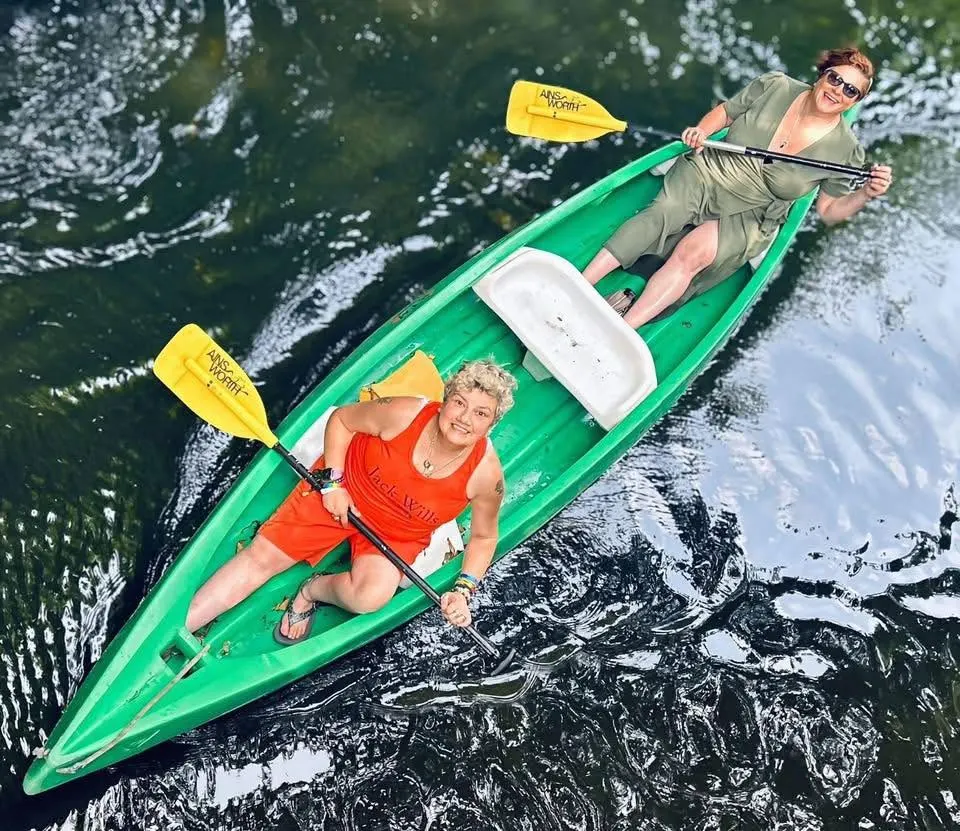 Two people kayaking in a bright green kayak on a lake, viewed from above.