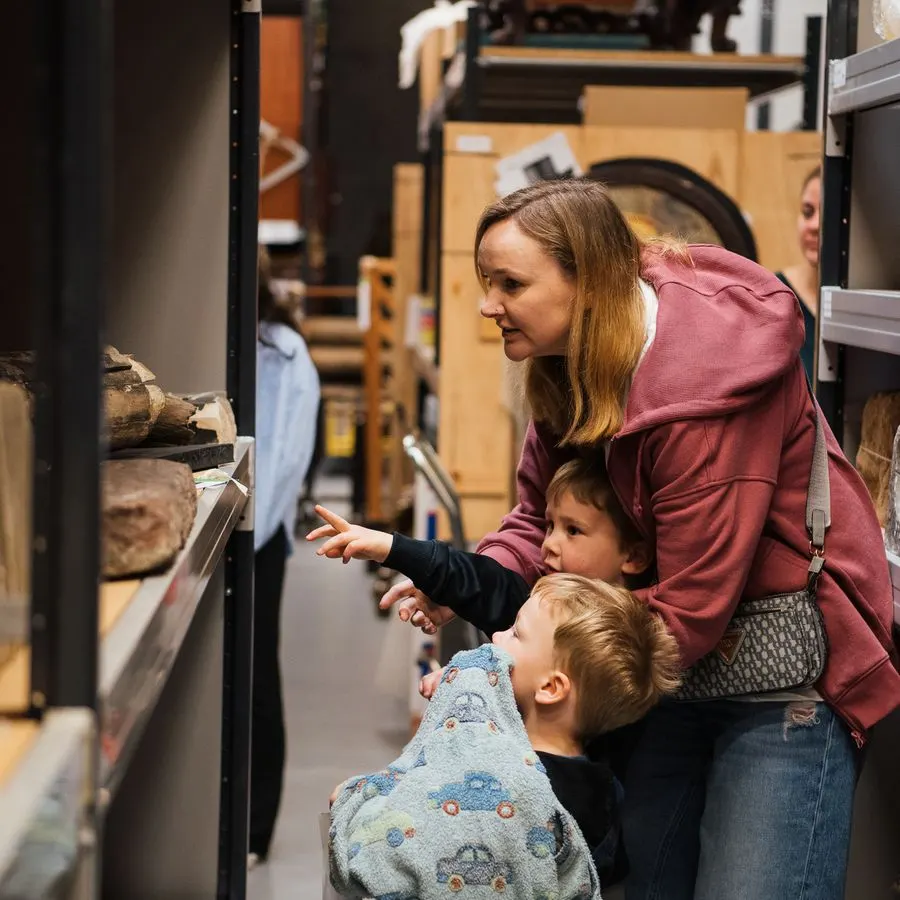 Woman and two young children viewing a display case in a museum or visitor centre.