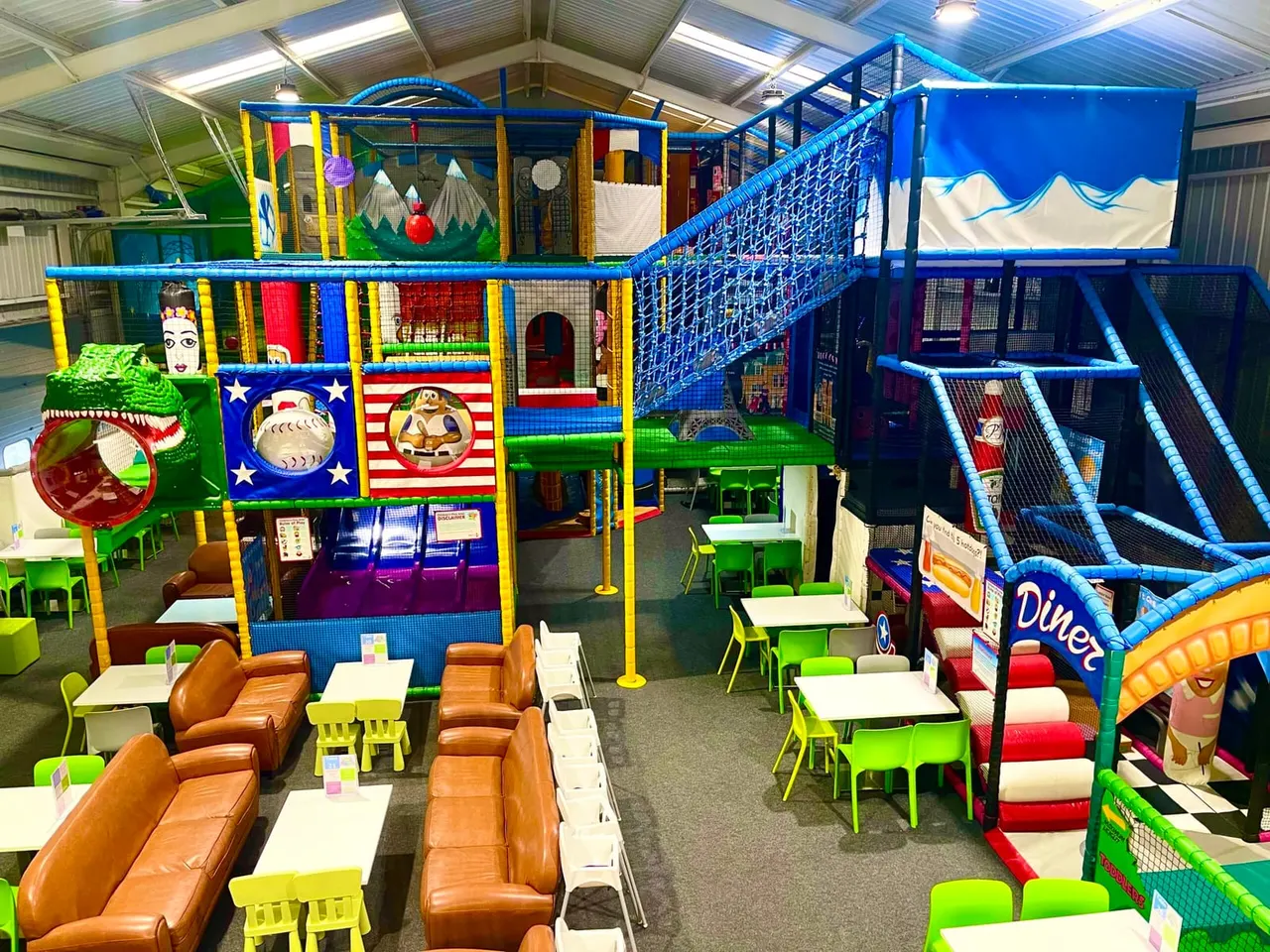 Large indoor play area with colorful climbing structures, slides, seating areas and activity zones for children.
