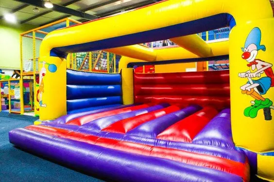A large inflatable bouncy castle with colourful sections in yellow, blue, red and purple in an indoor play centre.