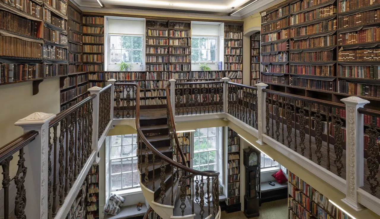 Interior of Bromley House Library with tall bookshelves and staircase