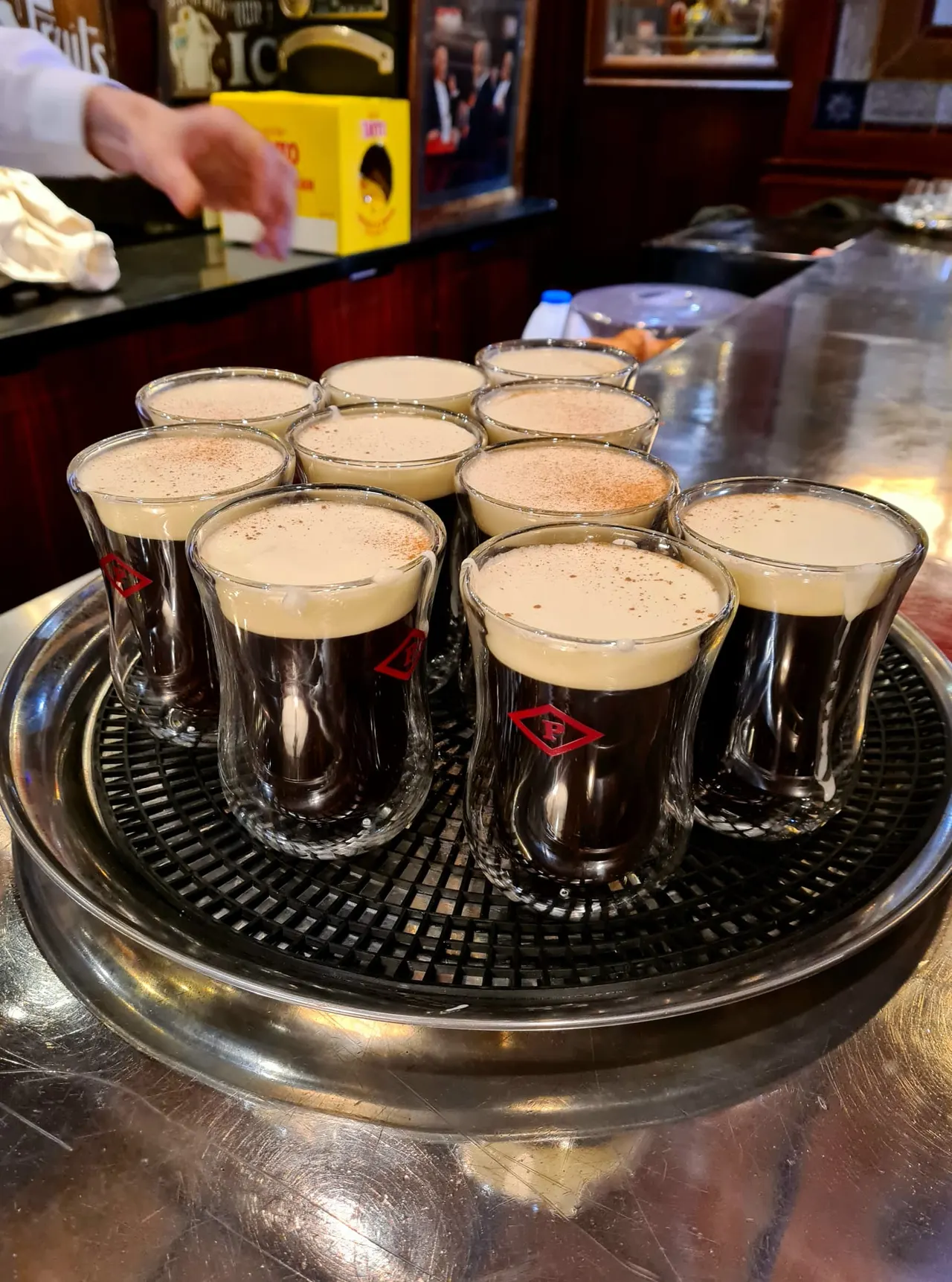 Multiple pints of stout with creamy heads arranged on a serving tray at a bar counter.