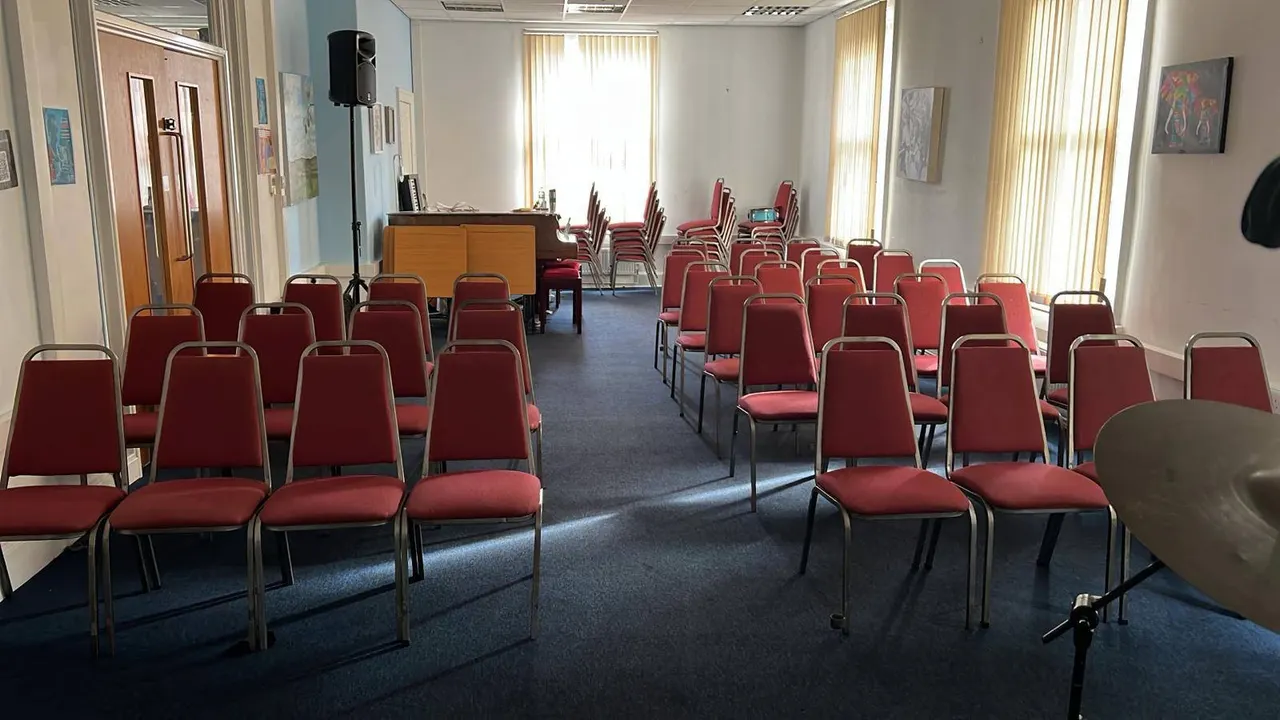 Empty function room with rows of red upholstered chairs arranged for an event or presentation.