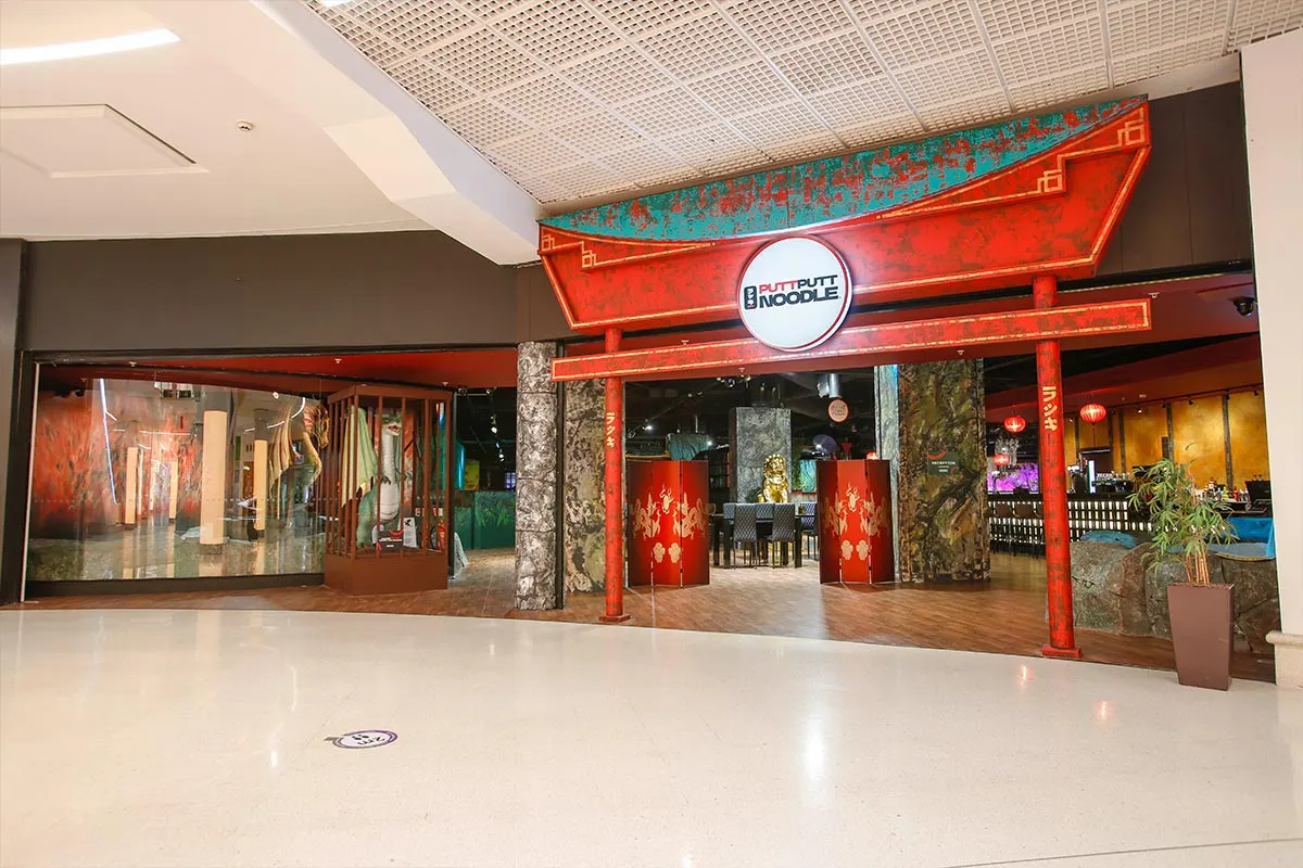 Restaurant storefront with red and turquoise Asian-inspired facade and neon signage in an indoor shopping centre.