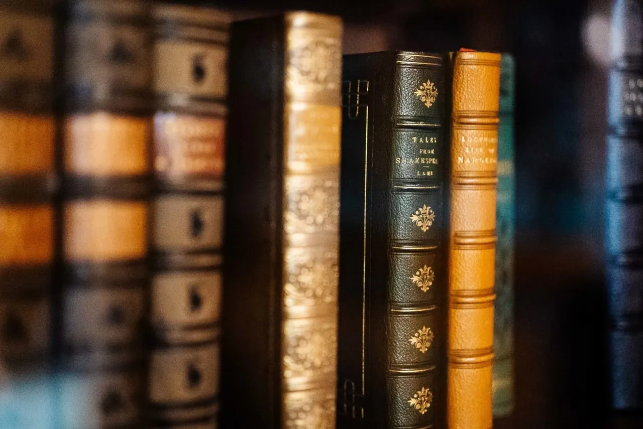 Row of antique leather-bound books on a shelf, including a dark green volume titled "Tales from Shakespeare".