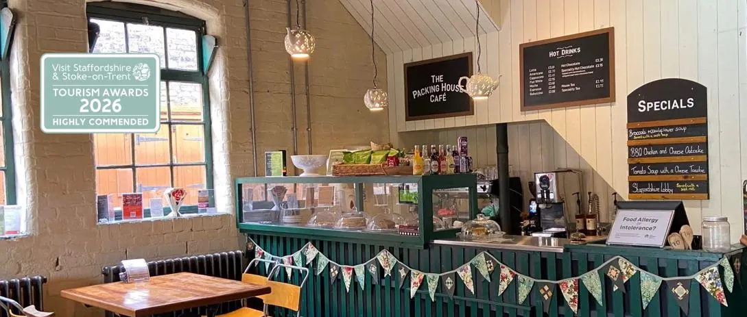 Interior of a café with green counter, wooden tables, menu boards, and decorative bunting.