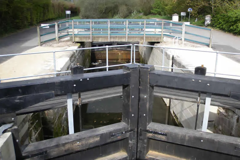 Canal lock gates open with a footbridge spanning the waterway above.