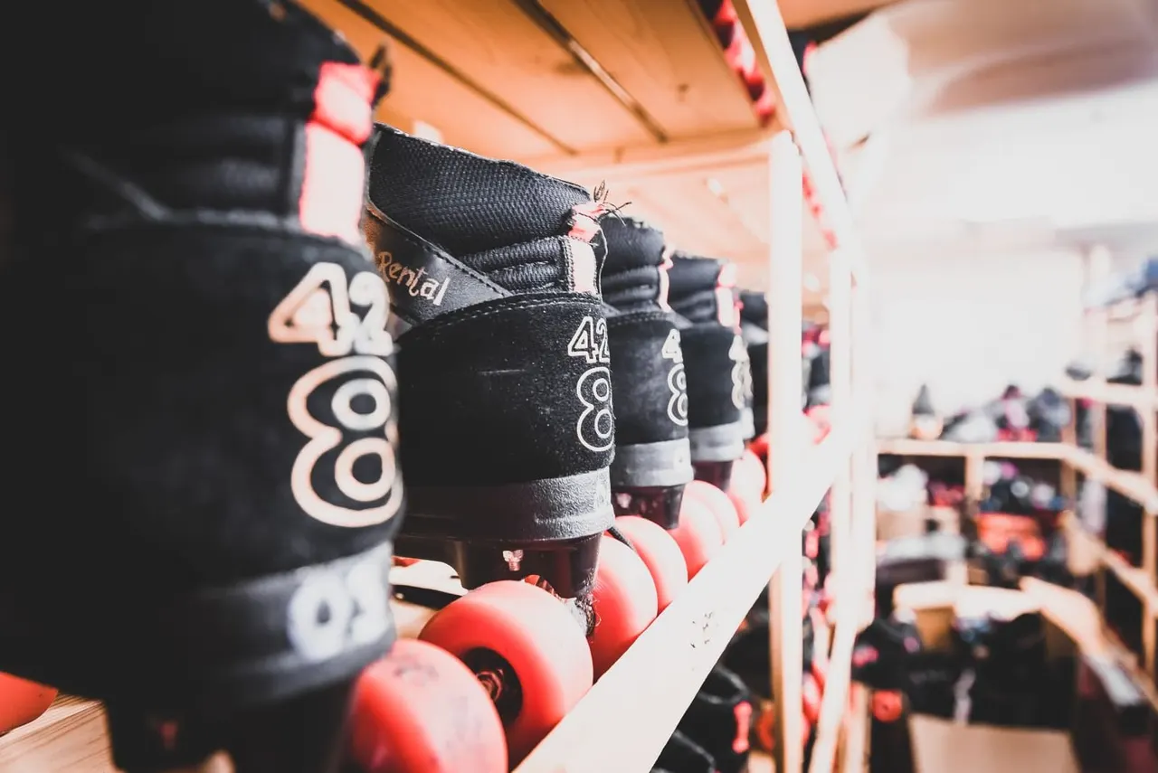 Row of black roller skates with red wheels displayed on a shelf.