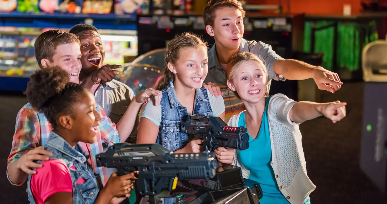 Group of children playing laser tag together, holding guns and smiling in an arcade venue.