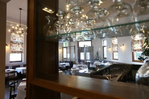 Fine dining restaurant interior with modern chandeliers, elegant table settings, and contemporary décor.