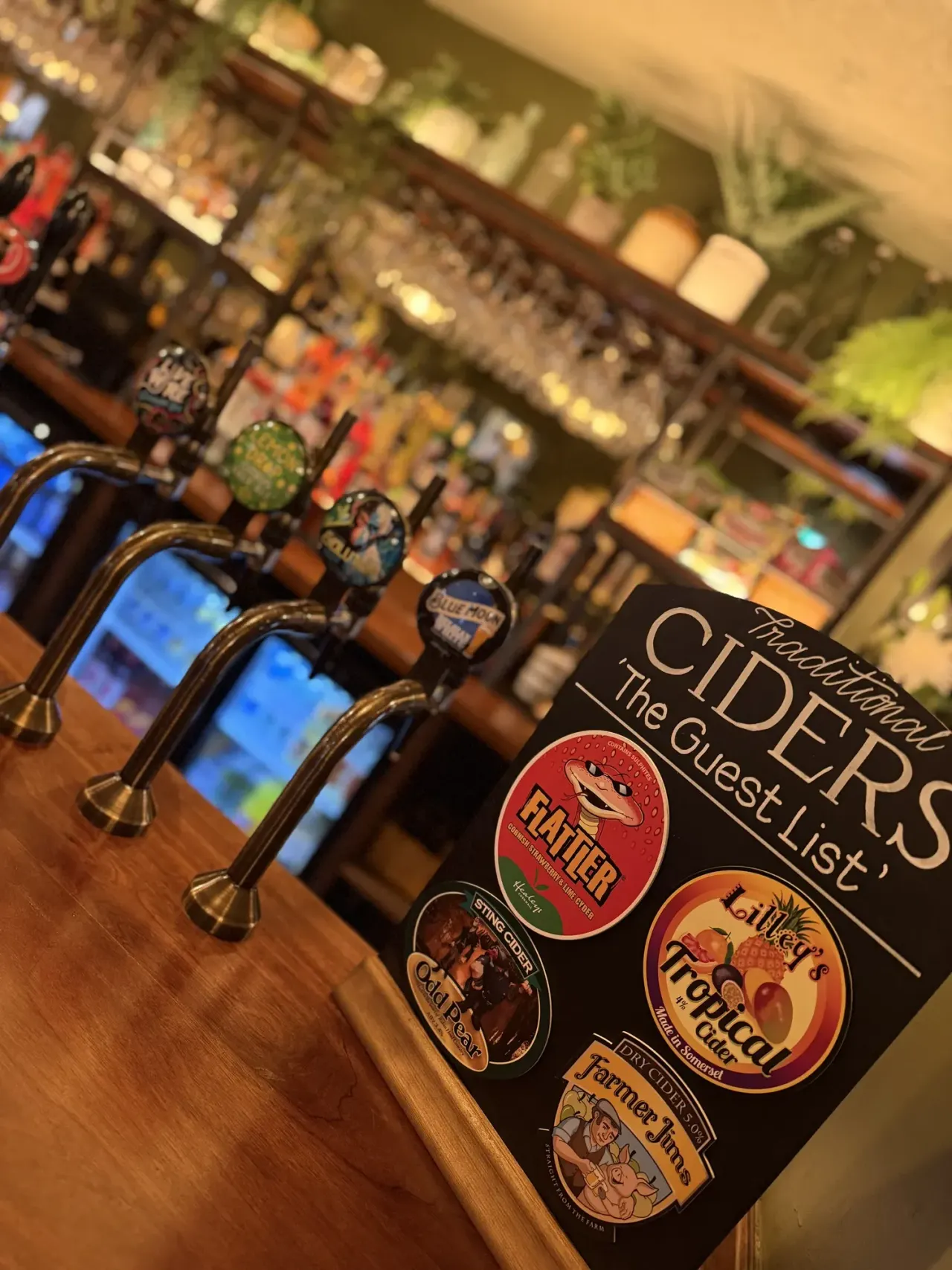 Beer pump handles with guest list board at bar counter.