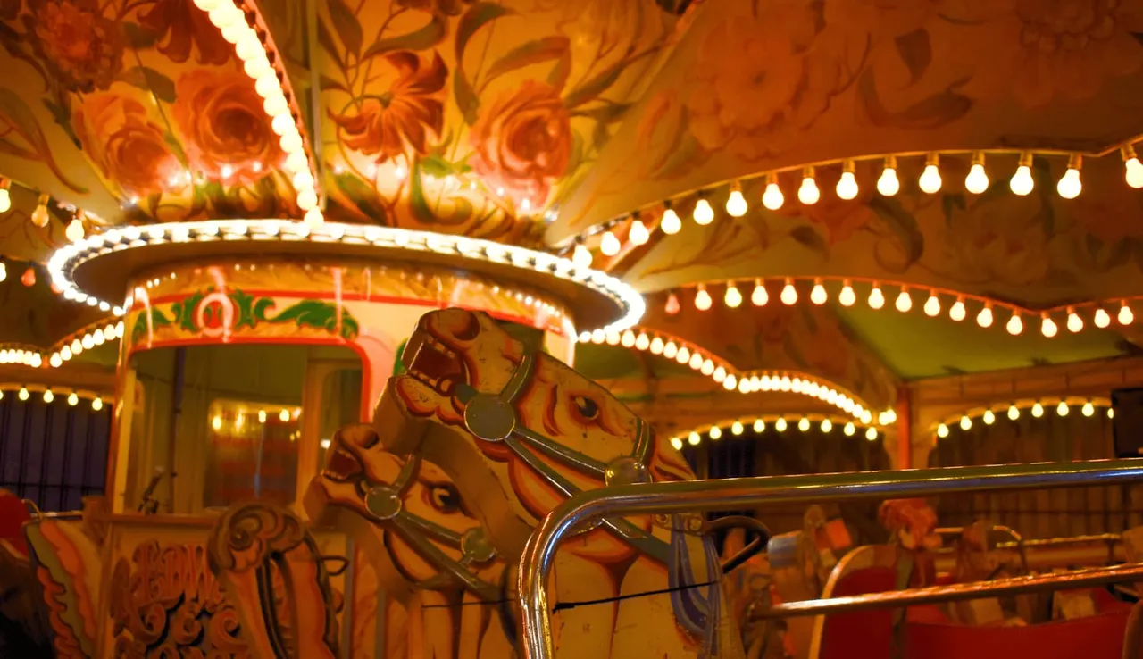 Ornately decorated carousel horse with illuminated bulbs and painted details on traditional fairground ride.