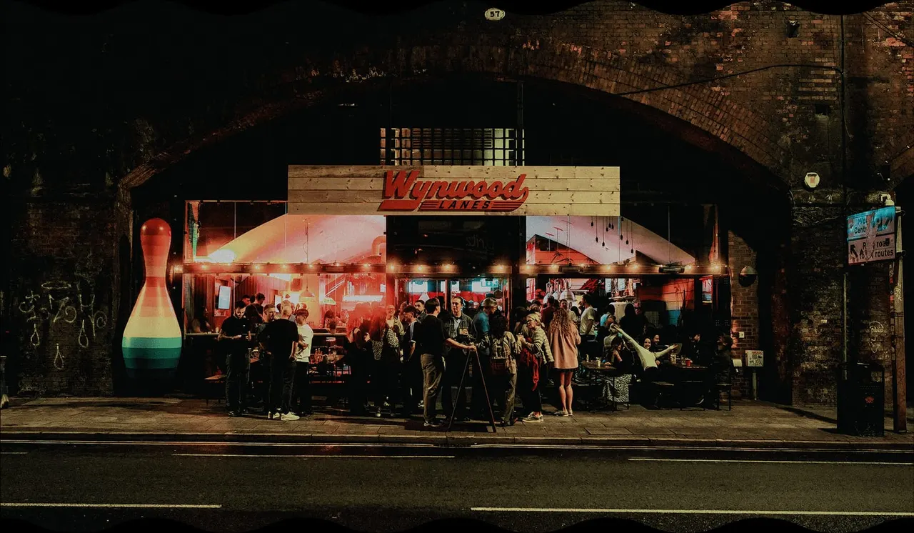 Wynwood Lanes bowling alley exterior at night with groups of people gathering outside the illuminated storefront.
