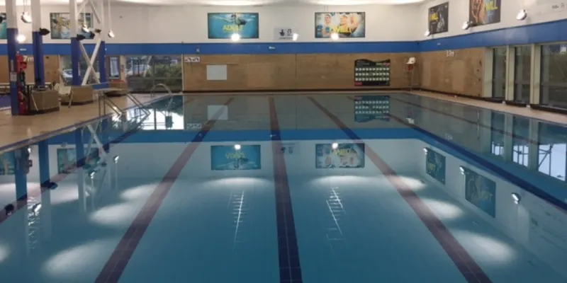 Indoor swimming pool with multiple lanes marked by lane dividers, viewed from poolside.