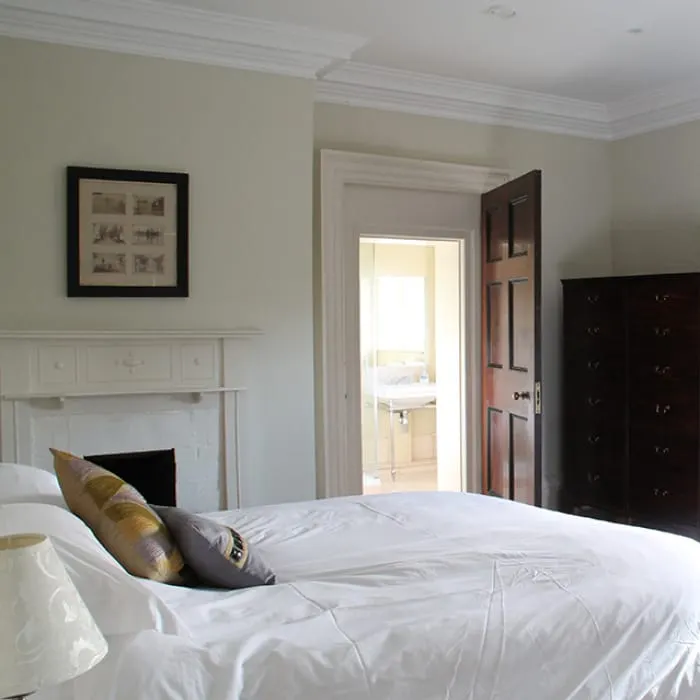 Spacious bedroom with white bedding, gold cushions, fireplace, and open door to en-suite bathroom.