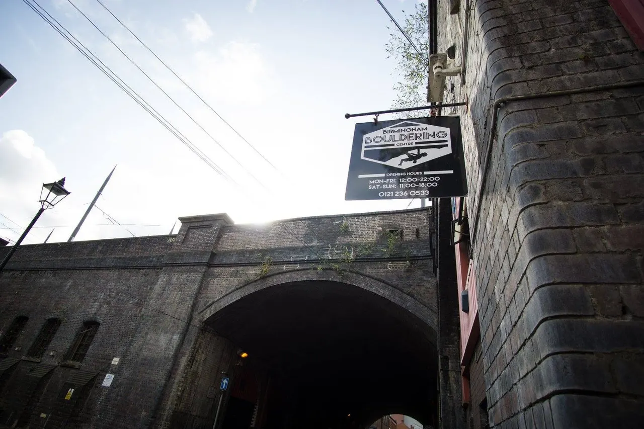 Signage for Birmingham Bouldering Centre on a brick building with a railway arch beneath it.