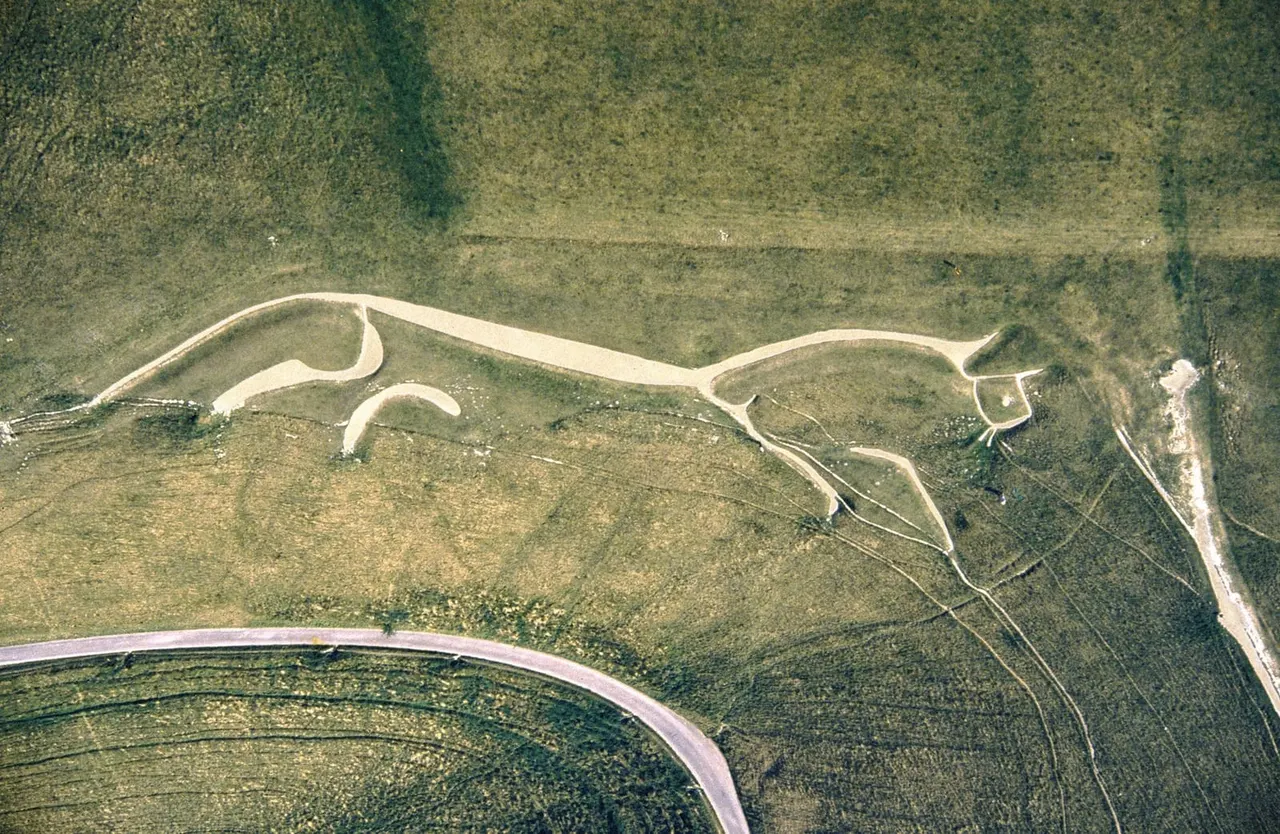 Aerial view of the Uffington White Horse, a geoglyph carved into chalk hillside with surrounding landscape and paths visible.